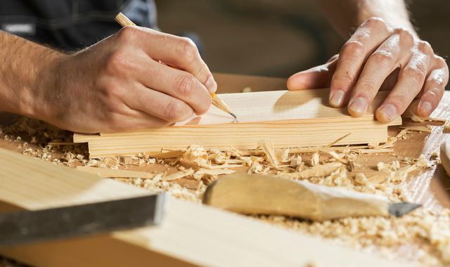 Menuisier qui trace un repère au crayon sur une planche de bois